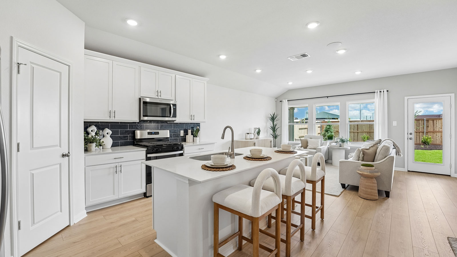 Modern kitchen with quartz countertops and navy blue tile backsplash.