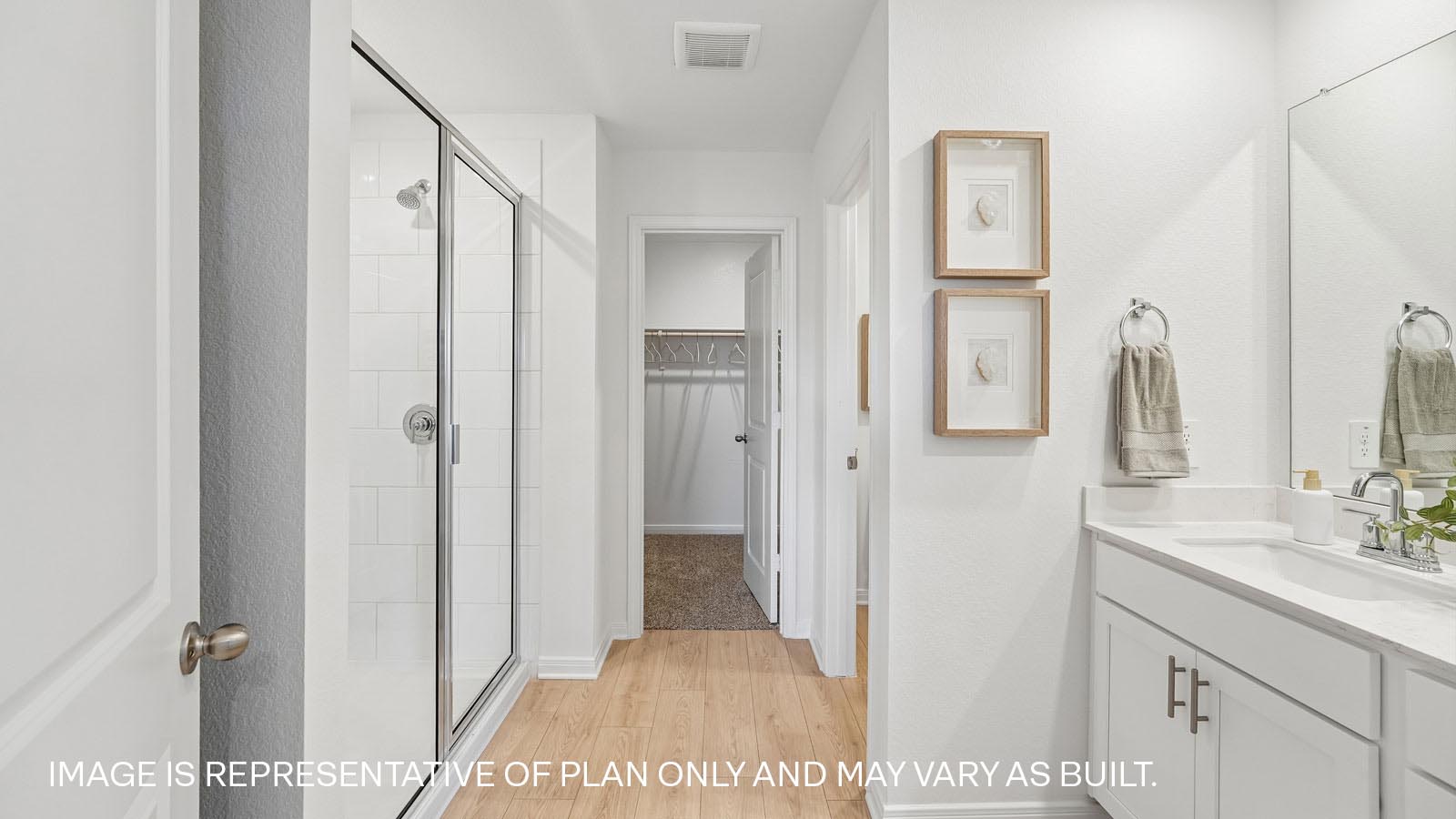 Primary ensuite bathroom with walk-in shower, walk-in closet, and double-vanity sink.
