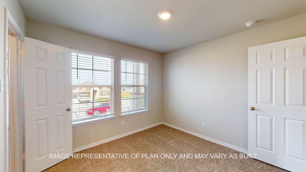 Auburn secondary bedroom with carpet flooring and windows.