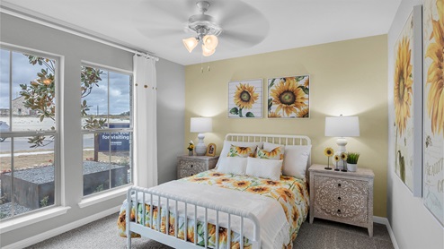 Creekfall model home secondary bedroom with full-size bed and carpet flooring.