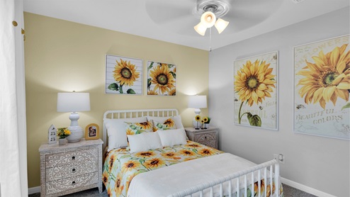 Creekfall model home secondary bedroom with full-size bed and accent decor.