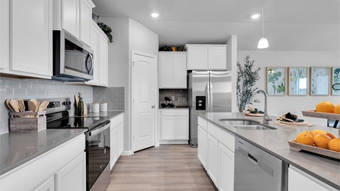 Creekfall model home kitchen with white cabinets and granite counters.