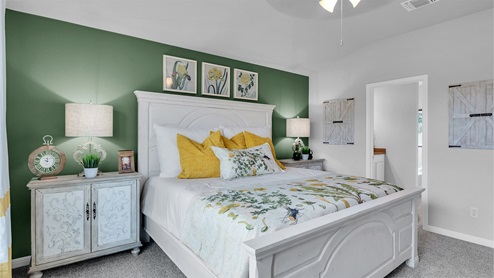 Creekfall model home primary bedroom with king size bed with view of primary bathroom.