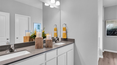 Creekfall model home primary bathroom with double vanity sink and granite countertops.