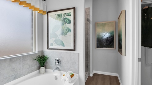 Creekfall model home primary bathroom with walk in shower and tub.