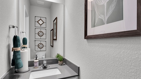 Creekfall model home powder room with vanity sink and granite countertops.