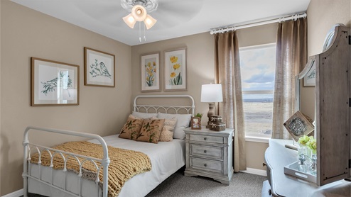 Creekfall model home secondary bedrrom with full-size bed and accent decor.