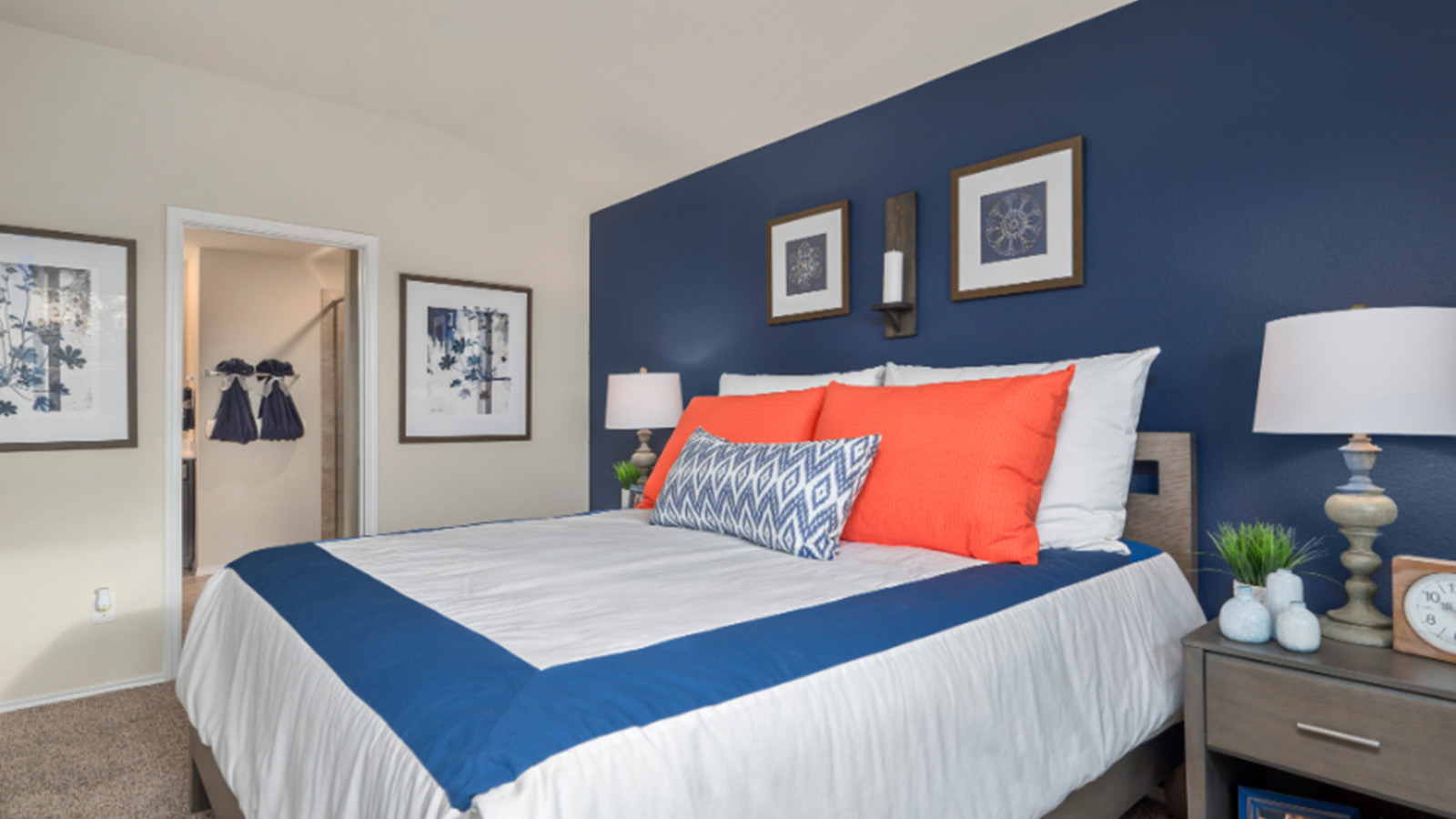 Yowell Ranch Model Home primary bedroom with carpeted flooring and view of primary bathroom.