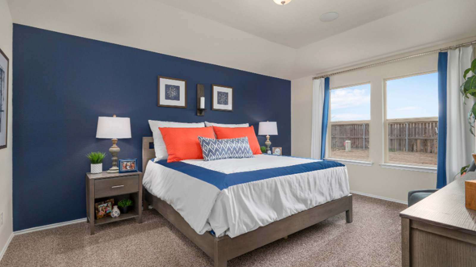 Yowell Ranch Model Home primary bedroom with carpeted flooring and windows for lighting.
