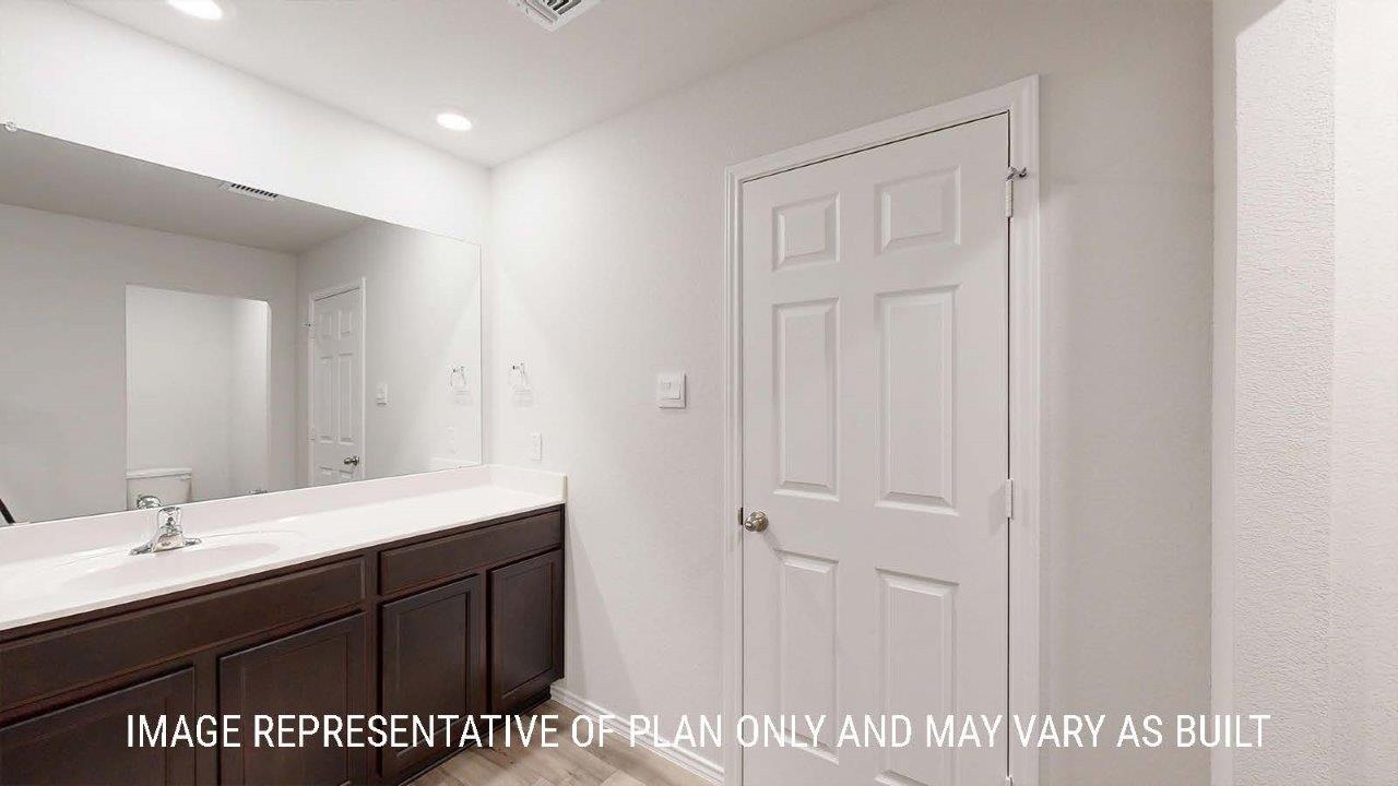 Emma primary bathroom with vanity sink and dark cabinets and granite countertops.