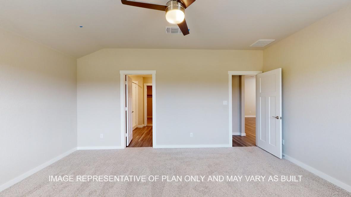 Caden primary bedroom with carpet flooring and access into primary bath.