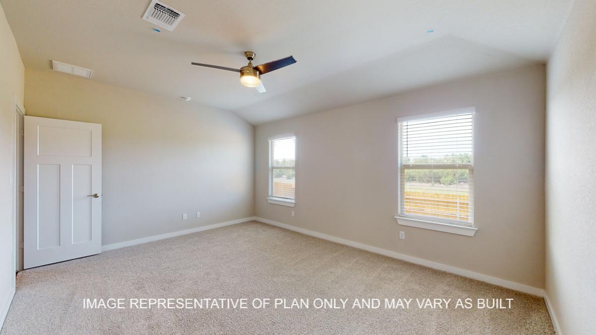 Caden primary bedroom with carpet flooring and windows to backyard.