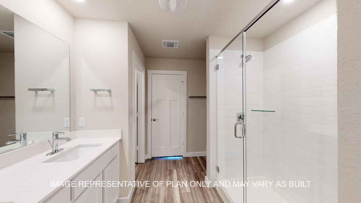 Caden primary bath with white cabinets and countertops and clear shower glass enclosure.