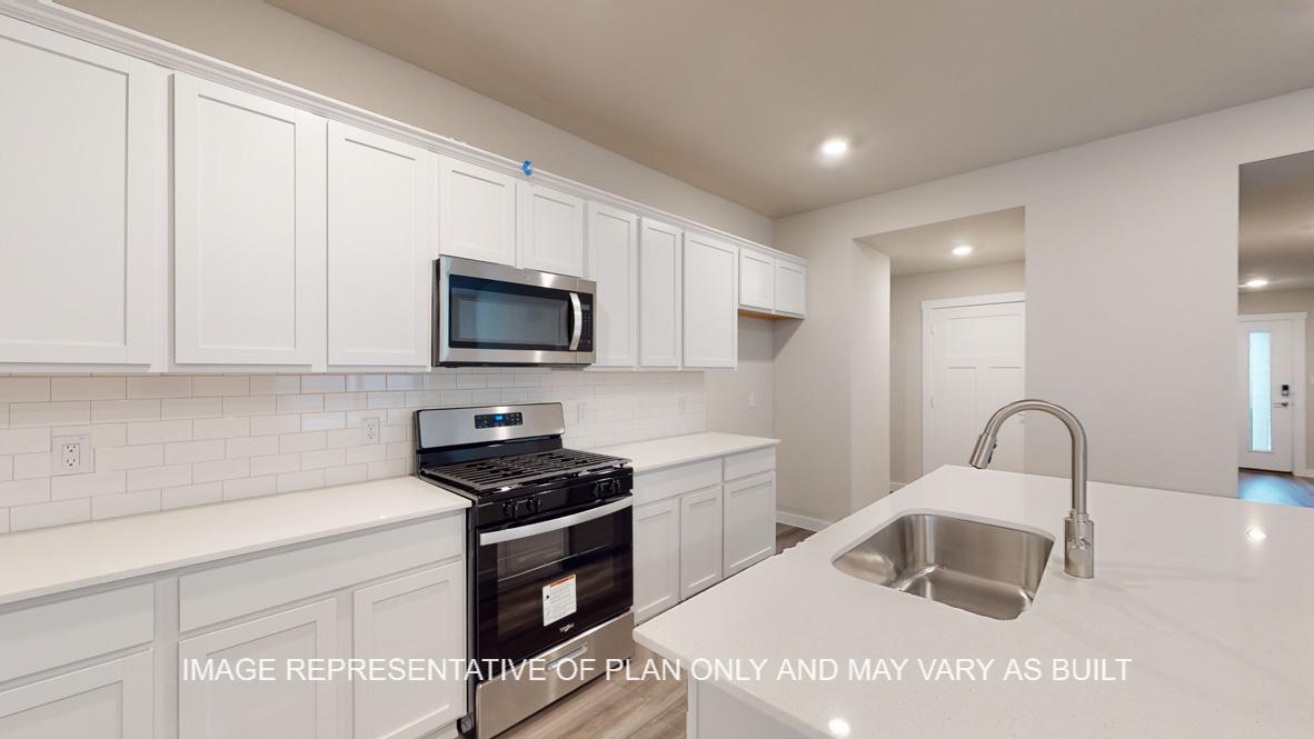 Caden kitchen with white cabinets and white quartz countertops.
