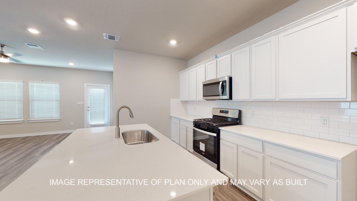 Caden kitchen with white cabinets and white quartz countertops.