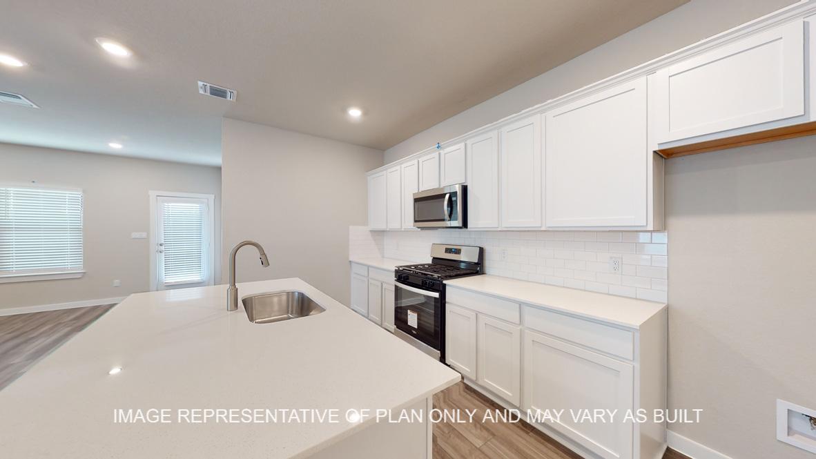 Caden kitchen with white cabinets and white quartz countertops.