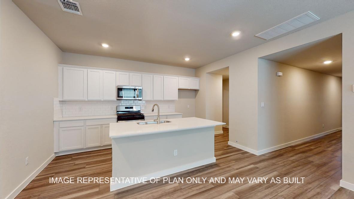 Caden kitchen with kitchen island, vinyl plank flooring and white cabinets.