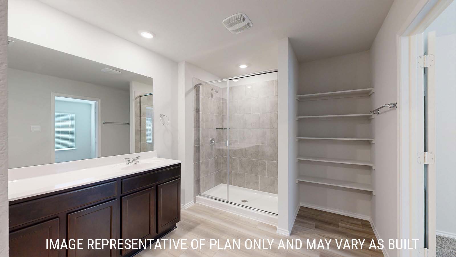 Gaven primary bathroom with white vanity counter and walk-in shower and shelving for storage.