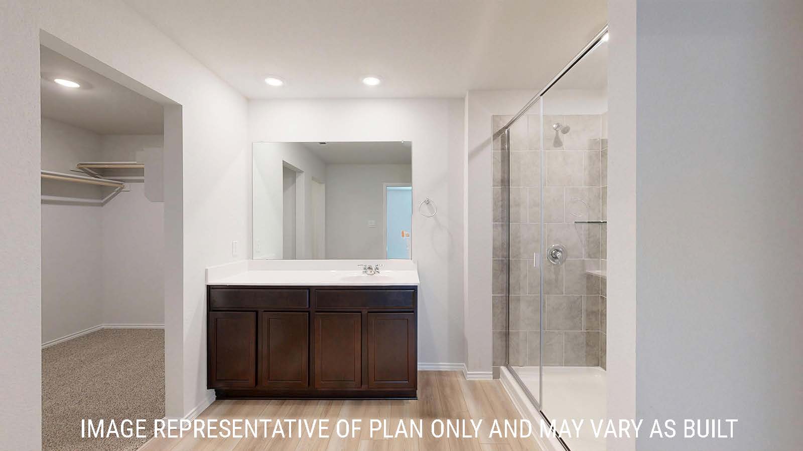 Gaven primary bathroom with white vanity counter and walk-in shower and view of primary closet.