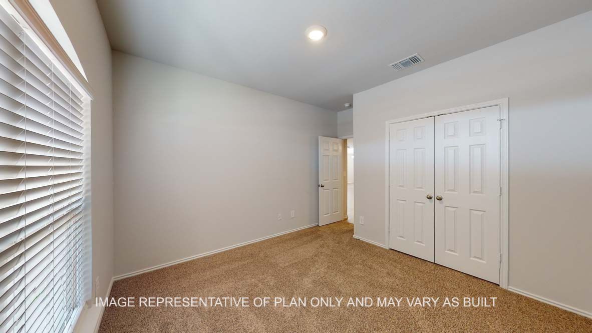 Roosevelt secondary bedroom with carpet flooring and closet doors.