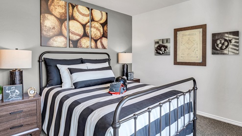 Three Creeks Colt Creek model home secondary bedroom with a full-size bed and carpet flooring.