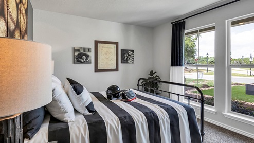 Three Creeks Colt Creek model home secondary bedroom with twin bed and carpet flooring.