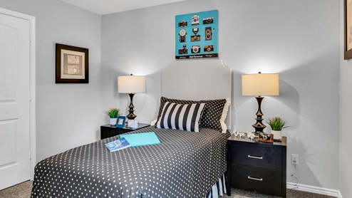 Three Creeks Colt Creek model home secondary bedroom with a twin bed and accent decor.