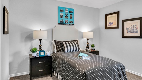 Three Creeks Colt Creek model home secondary bedroom with twin bed and carpet flooring.