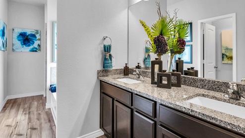 Three Creeks Colt Creek model home primary bathroom with a double vanity sink and mirror.