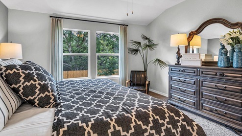Three Creeks Colt Creek model home primary bedroom with a king bed and accent decor.