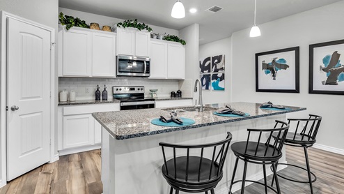 Three Creeks Colt Creek model home kitchen with white cabinets and granite countertops.