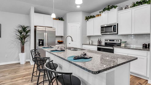 Three Creeks Colt Creek model home kitchen with white cabinets and granite countertops.