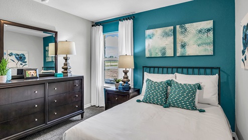 Three Creeks Colt Creek model home secondary bedroom with a full-size bed and accent decor.