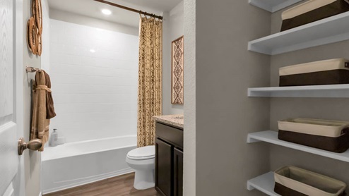 Park Meadows model home secondary bathroom with storage shelving, along with tub and shower combo.
