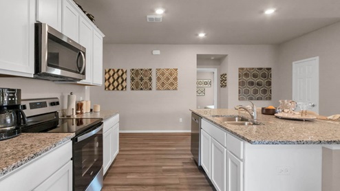 Park Meadows model home kitchen with white cabinets and granite countertops.