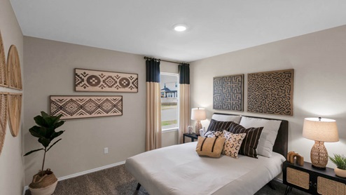 Park Meadows model home secondary bedroom with a full-size bed and accent decor.