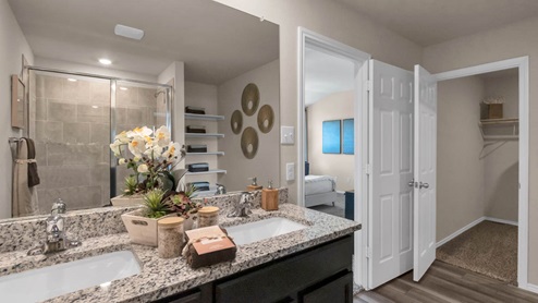 Park Meadows model home primary bathroom with double vanity sinks and walk-in closet.