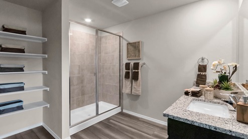Park Meadows model home primary bathroom with walk-in shower and granite countertops.
