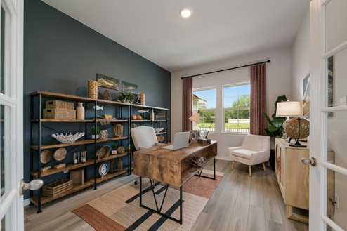 Foxborough model home secondary bedroom with storage shelving and a office desk and chair.