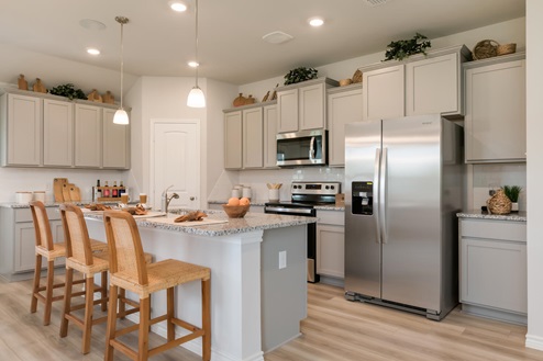 Foxborough model home kitchen with light cabinets and granite countertops.