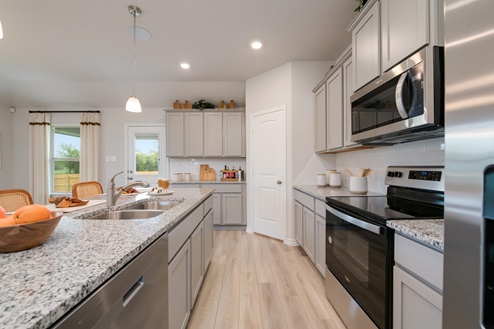 Foxborough model home kitchen with light cabinets and granite countertops.