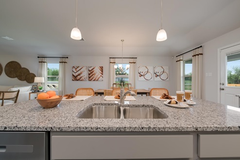 Foxborough model home kitchen sink with view of dining room.