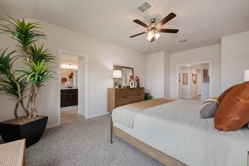 Foxborough model home primary bedroom with a king bed and view into primary bathroom.