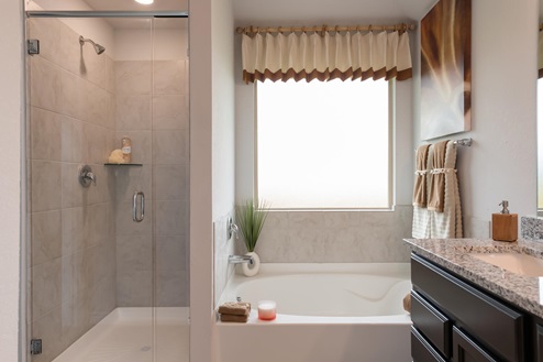 Foxborough model home primary bathroom with walk-in shower and soaking tub.