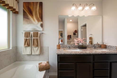Foxborough model home primary bathroom with soaking tub and double vanity sinks and mirror.