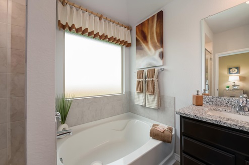 Foxborough model home primary bathroom with soaking tub and double vanity sinks and mirror.