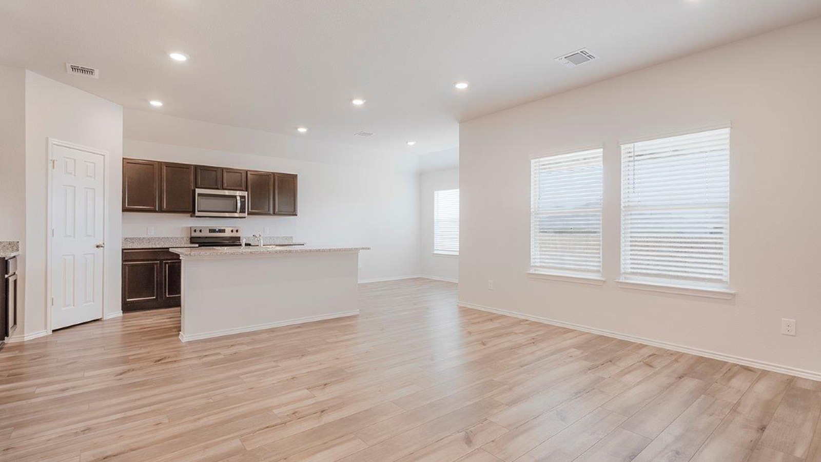 Schwertner Ranch living room with windows for natural lighting and view of open concept kitchen.