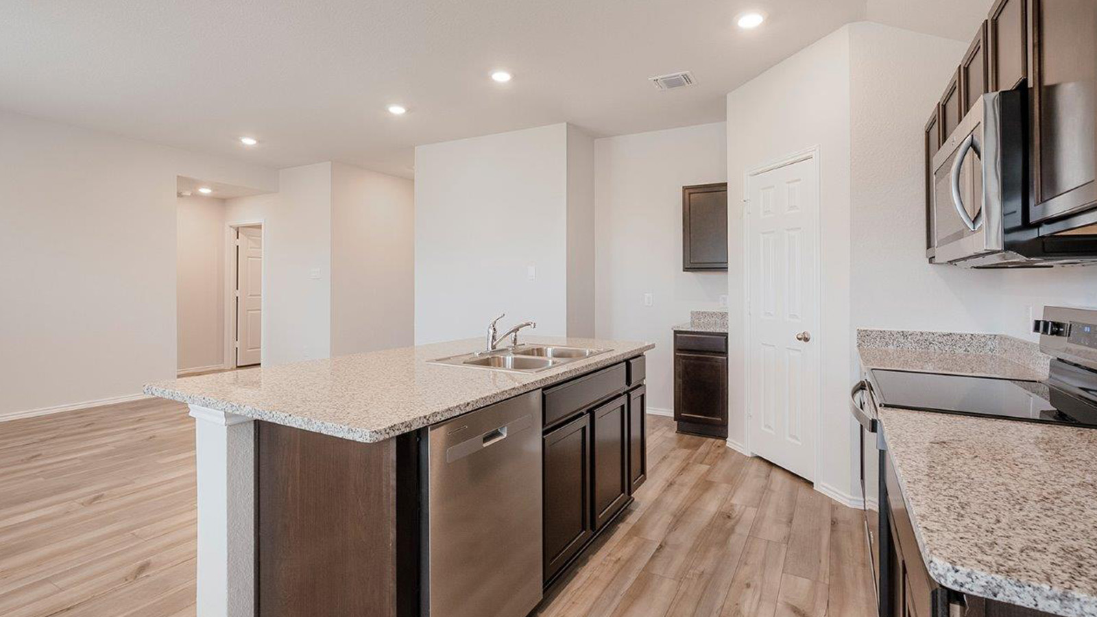 Schwertner Ranch kitchen with center kitchen island with granite countertops and dark cabinets.