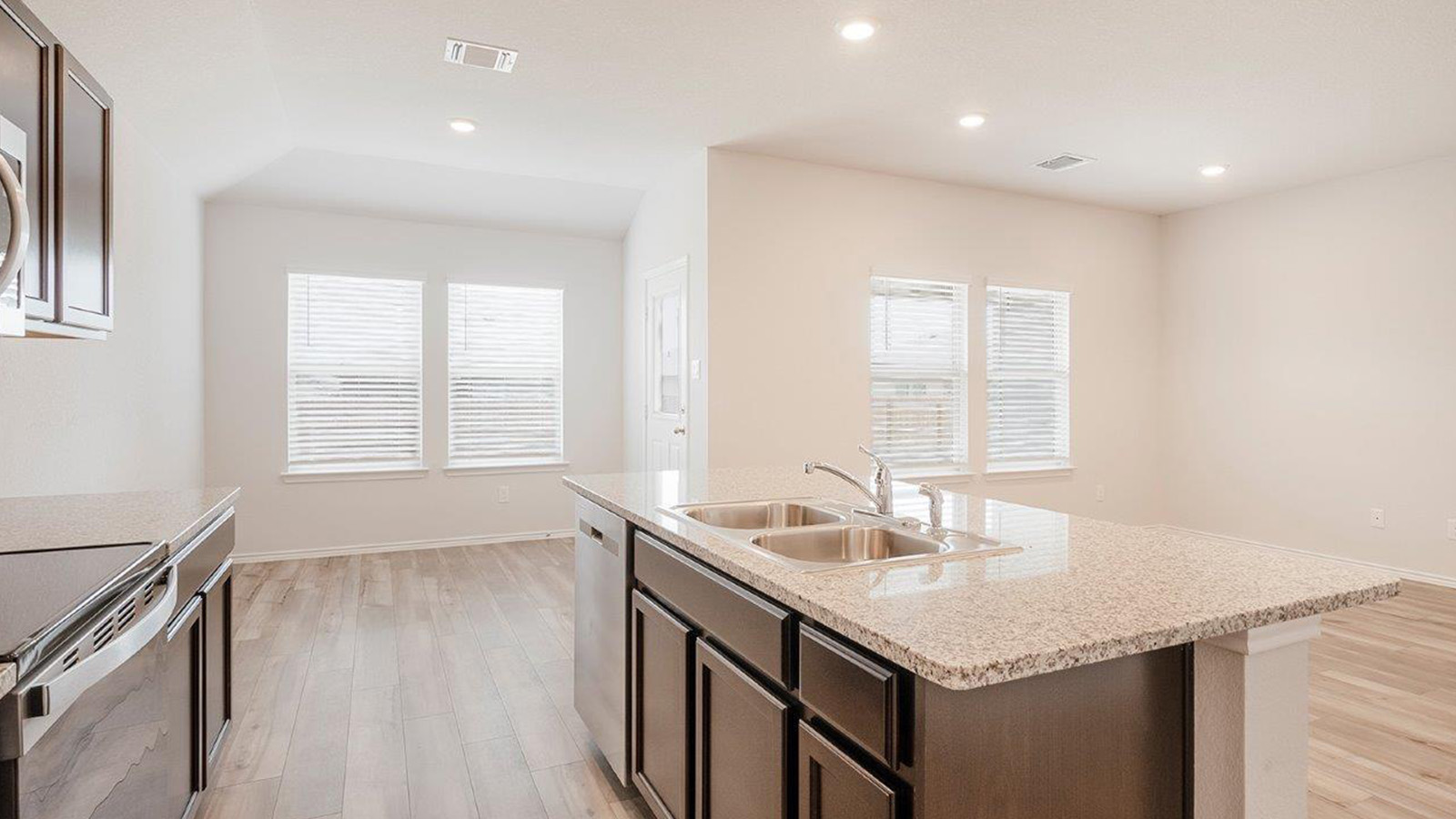 Schwertner Ranch kitchen with center kitchen island with granite countertops and dark cabinets.