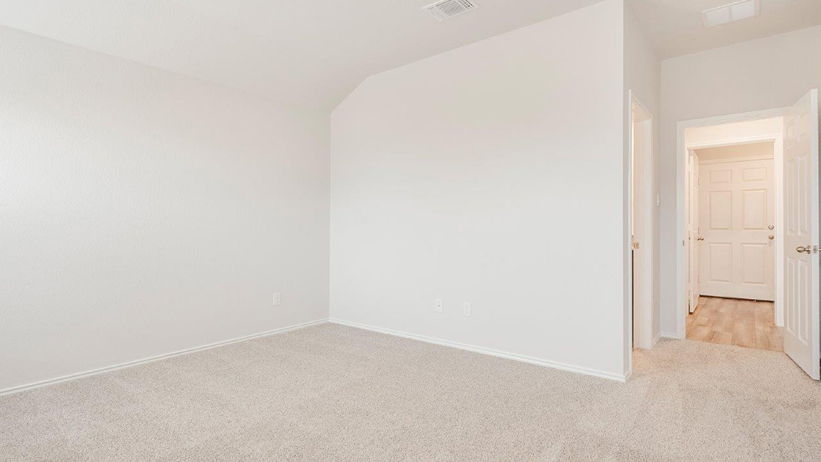 Schwertner Ranch primary bedroom with carpeted flooring and view of primary bathroom.